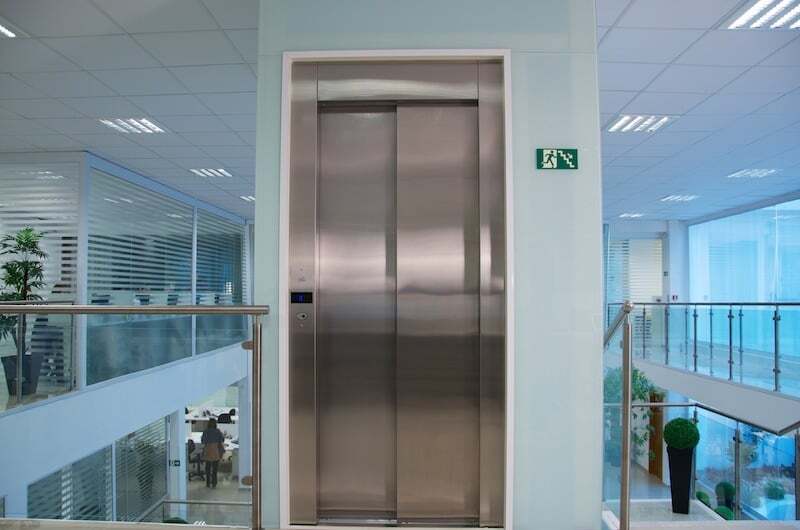O acabamento em inox e a face panorâmica do elevador hidráulico ressaltam os elementos arquitetônicos do local.